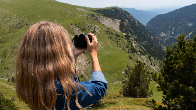 Photo d'une vallée verdoyante avec une femme qui prend une photo