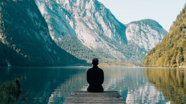 Photo d'un homme assis sur un ponton devant un lac