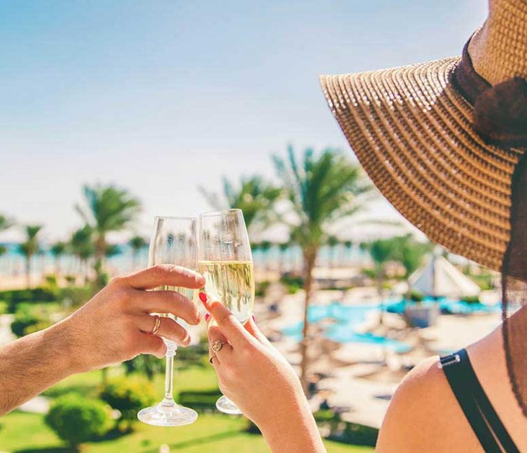 Une femme et un homme qui trinquent au bord de la piscine